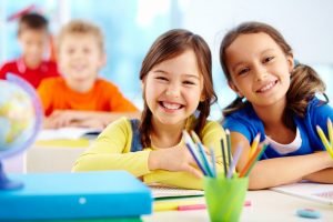 A pair of smiling students waiting in their classroom A pair of smiling students waiting in their classroom
