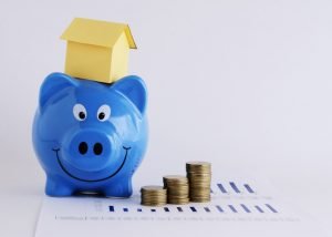 Piggy bank and paper house and coins stack for mortgage loans concept Piggy bank and paper house and coins stack for mortgage loans concept